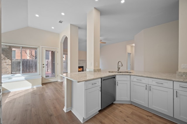 kitchen featuring kitchen peninsula, dishwasher, sink, light hardwood / wood-style floors, and light stone counters