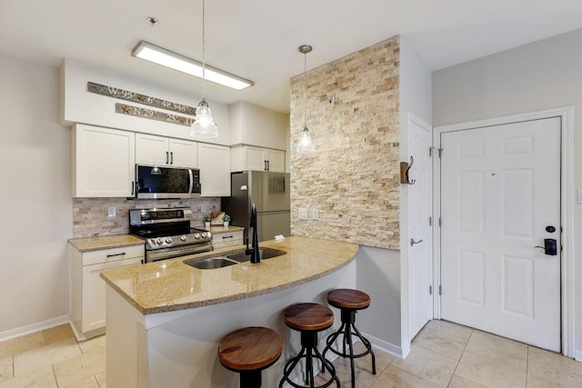 kitchen with light stone countertops, a sink, a breakfast bar area, stainless steel appliances, and decorative backsplash
