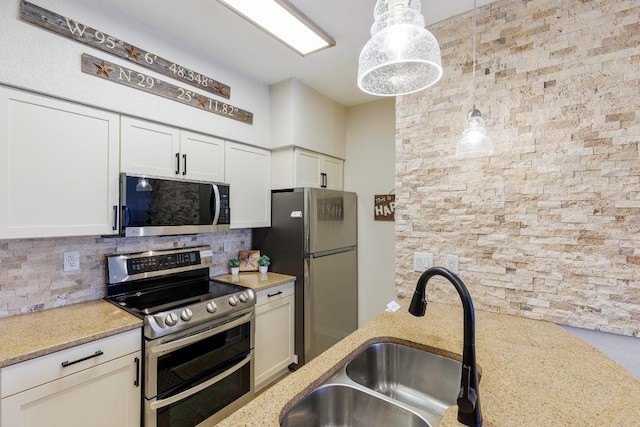 kitchen with appliances with stainless steel finishes, decorative light fixtures, sink, backsplash, and light stone countertops