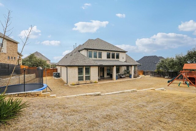 back of house with a trampoline, a yard, a patio, and a playground