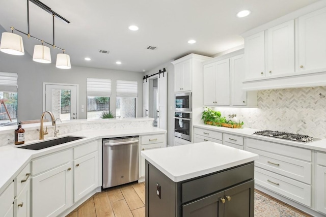 kitchen featuring sink, a barn door, white cabinets, and appliances with stainless steel finishes