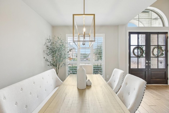 dining area featuring light wood-type flooring, a chandelier, and french doors