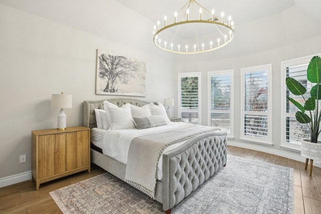 bedroom featuring hardwood / wood-style flooring, a tray ceiling, and a chandelier