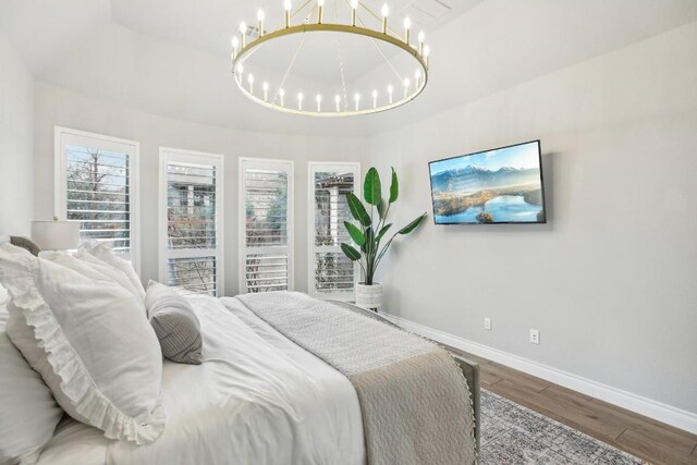 bedroom with a notable chandelier, wood-type flooring, and a raised ceiling