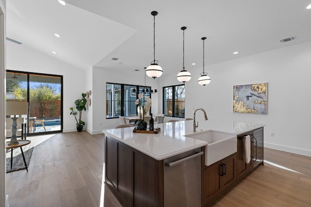 kitchen featuring sink, light wood-type flooring, dishwasher, an island with sink, and pendant lighting