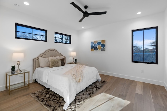 bedroom with multiple windows, ceiling fan, and light wood-type flooring