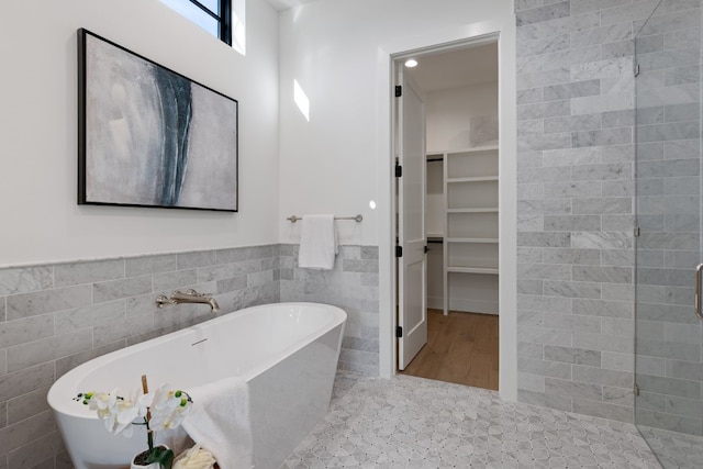 bathroom featuring independent shower and bath, tile patterned flooring, and tile walls