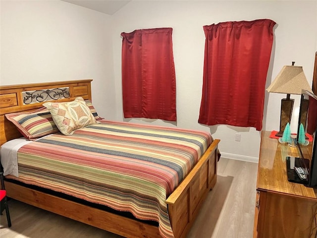 bedroom with lofted ceiling and light wood-type flooring