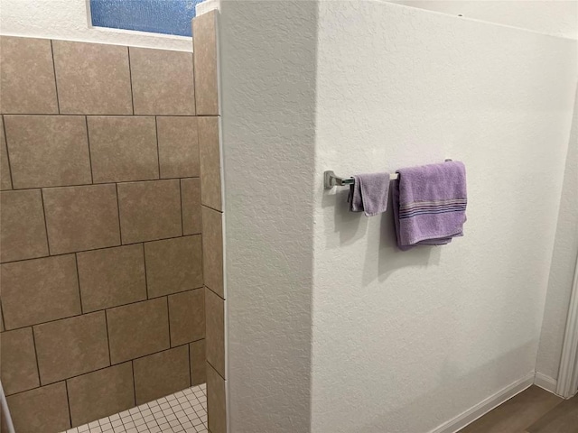 bathroom with hardwood / wood-style flooring and tiled shower