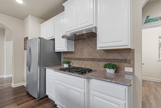 kitchen with dark wood-type flooring, white cabinetry, dark stone counters, stainless steel appliances, and decorative backsplash