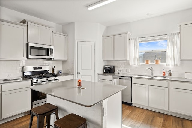 kitchen featuring a breakfast bar, sink, a center island, light hardwood / wood-style floors, and stainless steel appliances