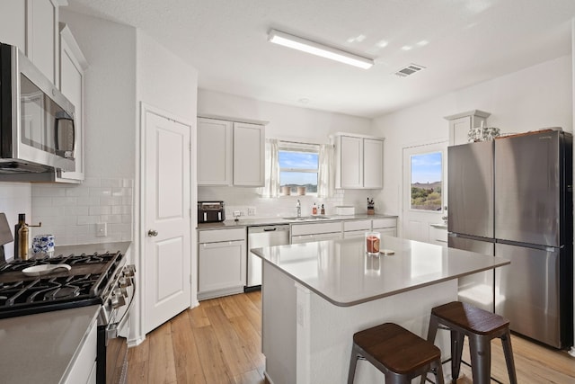 kitchen with sink, white cabinets, a kitchen breakfast bar, a center island, and stainless steel appliances