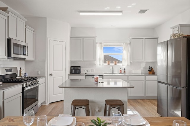 kitchen featuring a kitchen island, appliances with stainless steel finishes, a breakfast bar, sink, and light hardwood / wood-style floors