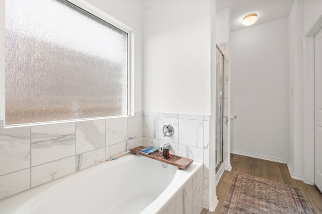 bathroom featuring a healthy amount of sunlight, plus walk in shower, and wood-type flooring