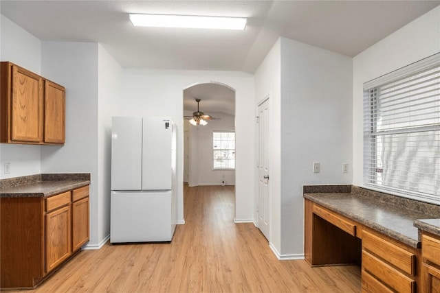 kitchen featuring ceiling fan, built in desk, white fridge, and light hardwood / wood-style flooring