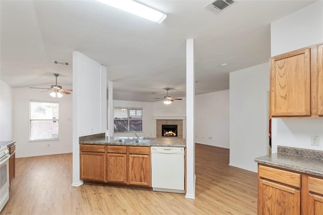 kitchen featuring sink, a tiled fireplace, ceiling fan, white appliances, and light hardwood / wood-style flooring