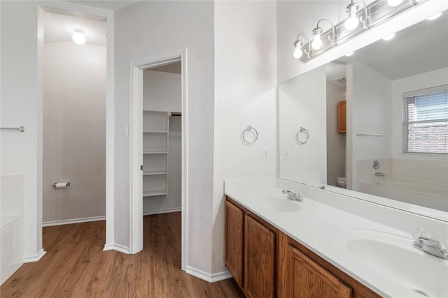 bathroom featuring hardwood / wood-style flooring, a bathing tub, vanity, and toilet