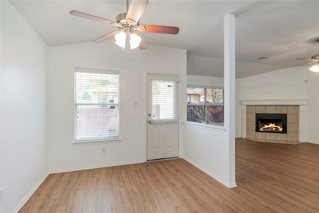 foyer entrance with lofted ceiling, a fireplace, and light wood-type flooring