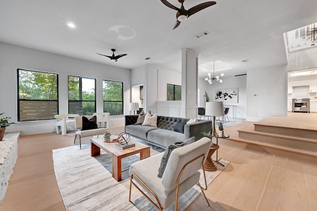 living room with ceiling fan with notable chandelier and light hardwood / wood-style floors