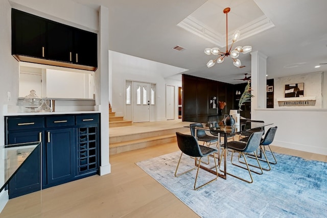 dining room featuring crown molding, light hardwood / wood-style flooring, a raised ceiling, and a chandelier