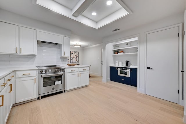 kitchen with stainless steel appliances, white cabinets, light wood-type flooring, and decorative backsplash