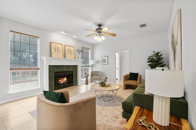 living room featuring ceiling fan, a tile fireplace, and light tile patterned floors