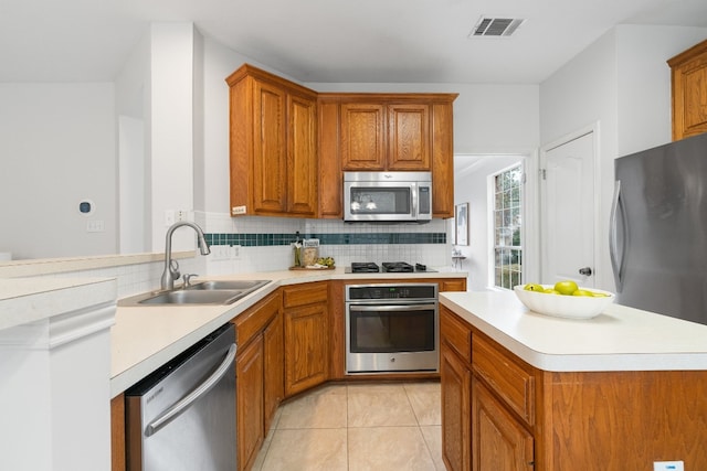 kitchen with appliances with stainless steel finishes, sink, light tile patterned floors, and decorative backsplash