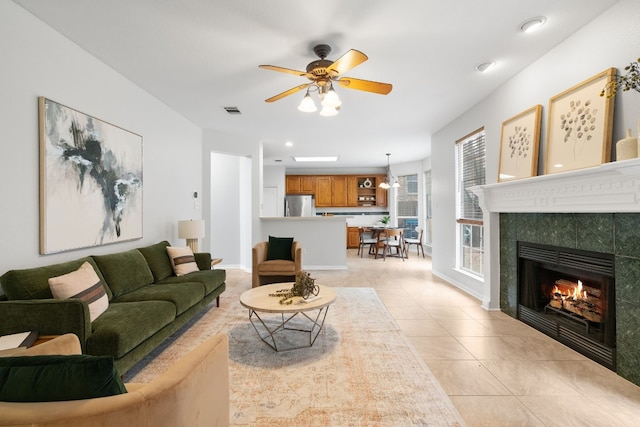 living room with light tile patterned flooring, ceiling fan, and a tiled fireplace