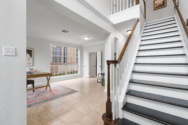 foyer featuring crown molding, a towering ceiling, and light tile patterned floors