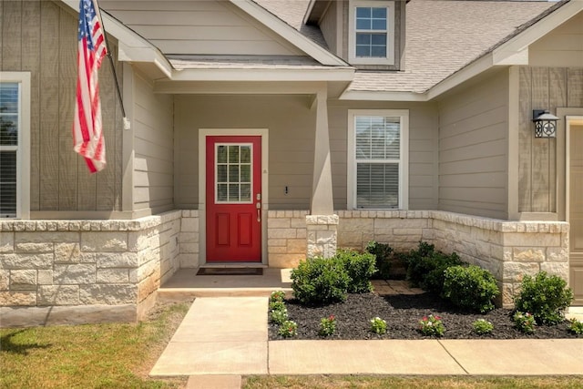 entrance to property with stone siding and roof with shingles