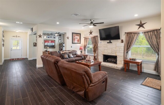 living room featuring dark hardwood / wood-style flooring, a stone fireplace, and a healthy amount of sunlight