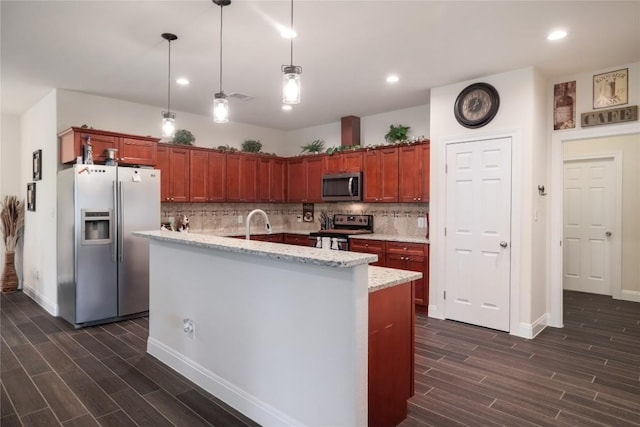 kitchen with stainless steel appliances, wood tiled floor, pendant lighting, and decorative backsplash