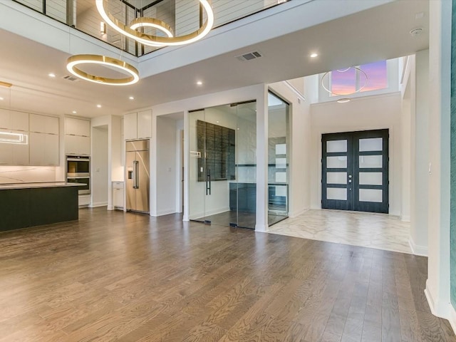 entrance foyer featuring a high ceiling, light hardwood / wood-style floors, and french doors