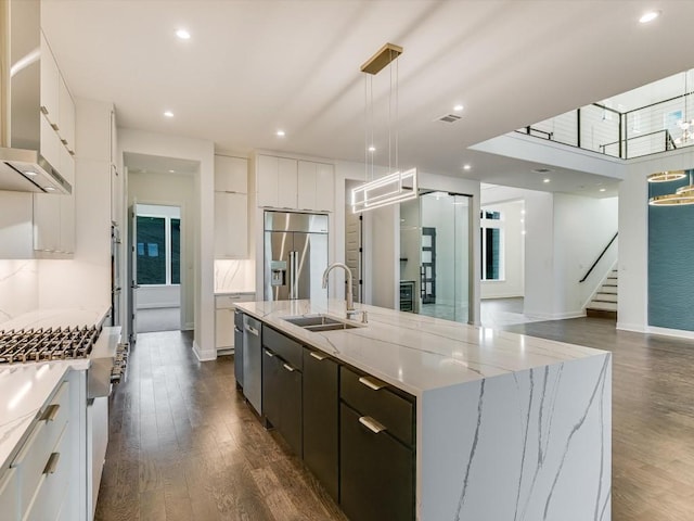 kitchen featuring sink, decorative light fixtures, stainless steel appliances, a kitchen island with sink, and white cabinets