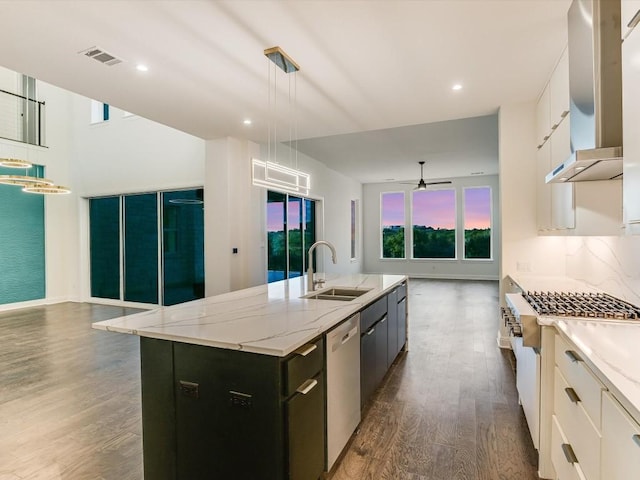 kitchen with sink, white cabinetry, hanging light fixtures, appliances with stainless steel finishes, and a kitchen island with sink