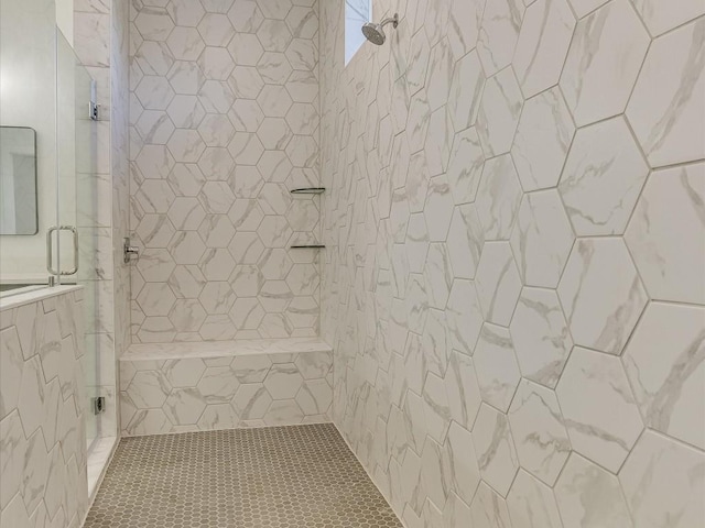 bathroom with tiled shower and tile patterned flooring