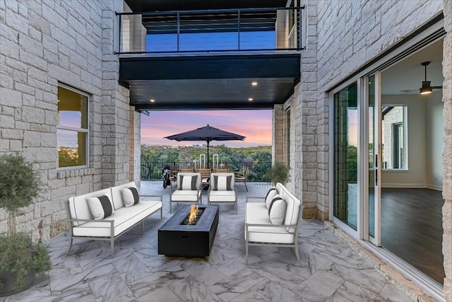 patio terrace at dusk with an outdoor living space with a fire pit