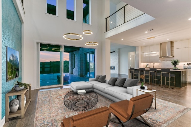 living room with sink, light hardwood / wood-style floors, and a high ceiling