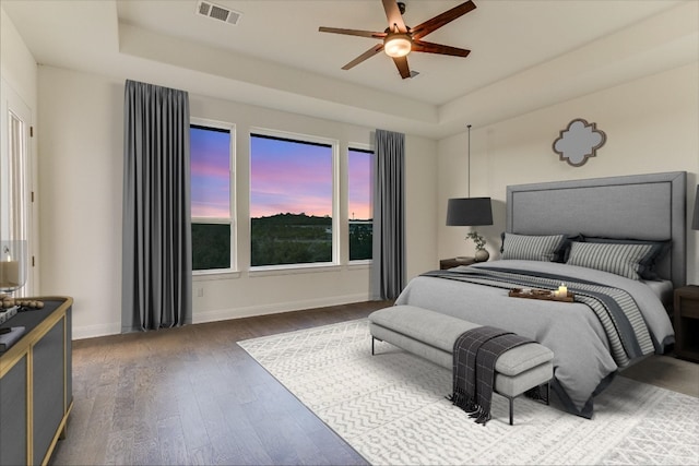 bedroom with dark wood-type flooring, a raised ceiling, and ceiling fan