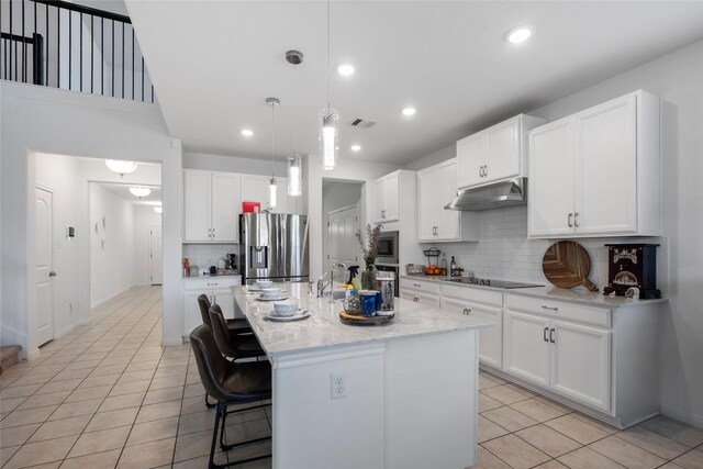 19405 Colgin Dr, Pflugerville, TX 78660 - kitchen with stainless steel appliances, under cabinet range hood, light tile patterned floors, tasteful backsplash, and white cabinetry