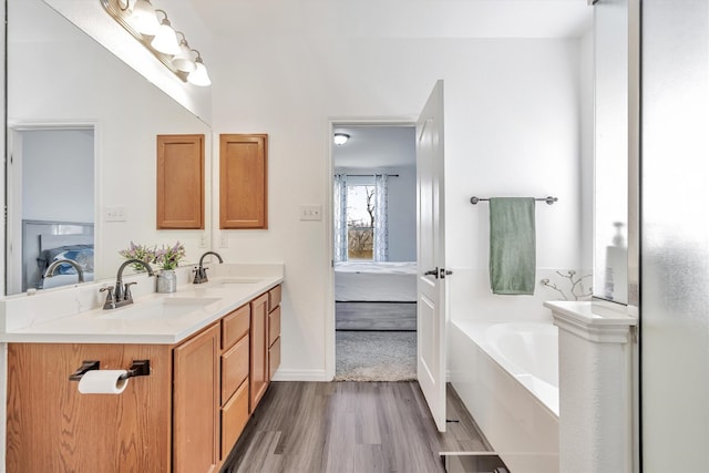 bathroom with a tub to relax in, wood-type flooring, and vanity