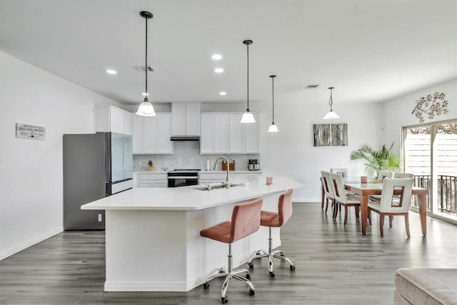 kitchen featuring sink, white cabinetry, tasteful backsplash, a center island with sink, and pendant lighting