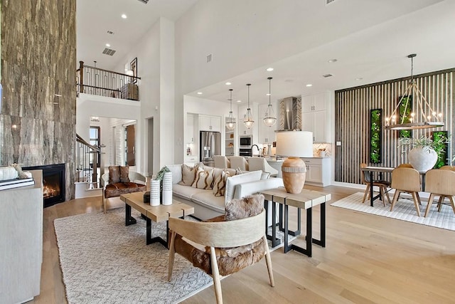 living room with light hardwood / wood-style flooring, a large fireplace, and a chandelier