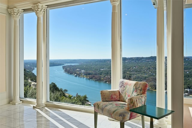 interior space with a water view, light tile patterned flooring, and ornate columns