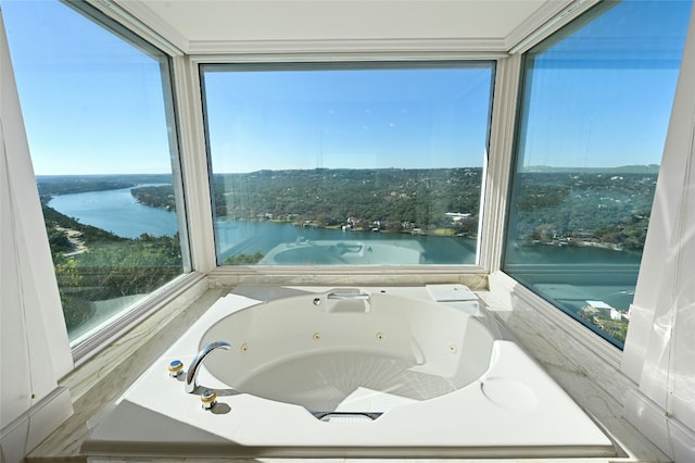 bathroom featuring a washtub, plenty of natural light, and a water view