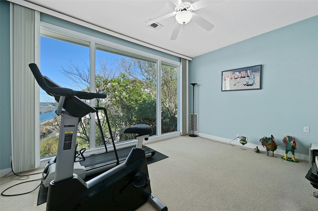 workout area featuring light colored carpet, expansive windows, ceiling fan, and a water view