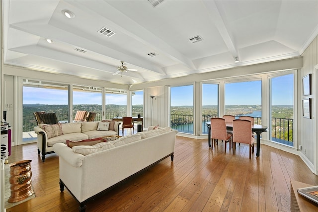 living room with a water view, ceiling fan, wood-type flooring, and beam ceiling