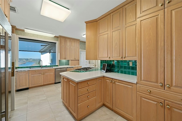 kitchen featuring sink, light tile patterned floors, appliances with stainless steel finishes, kitchen peninsula, and backsplash