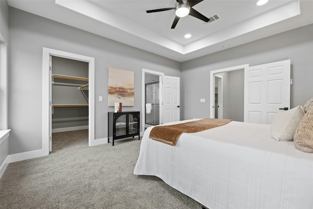 bedroom featuring ensuite bathroom, a tray ceiling, carpet floors, a walk in closet, and a closet