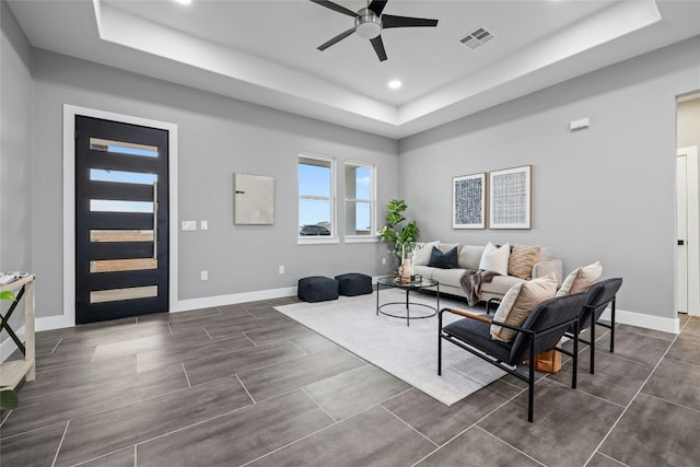 living room featuring a tray ceiling and ceiling fan